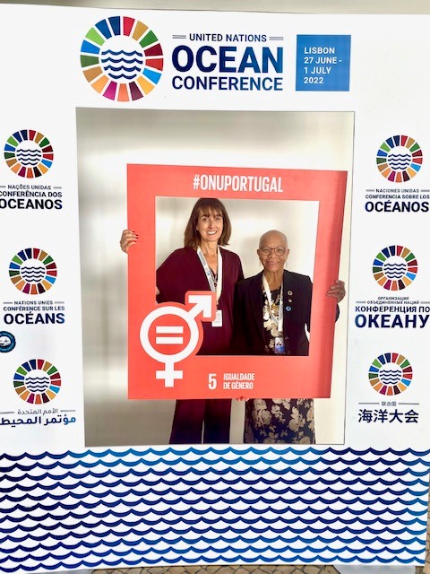 Rita and Dr. Cleopatra Doumbia-Henry hold up a Sustainable Develpment Goal 5 sign which reads "#onuportugal" with the gender equal symbol.